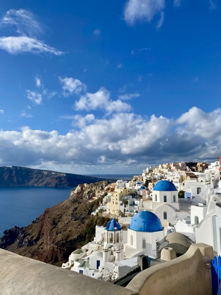 White cave houses and blue-domed churches above the caldera in Oia, Santorini, Greece