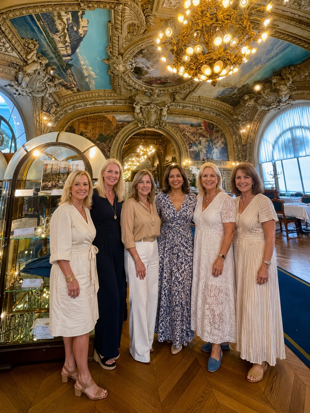 A group of women friends raising champagne glasses at Le Train Bleu restaurant in Paris, France