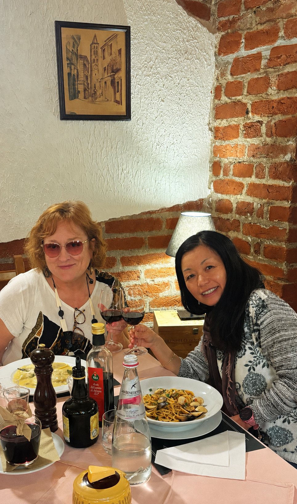 Friends sharing dinner and wine at a candlelit trattoria table in Tuscany, Italy
